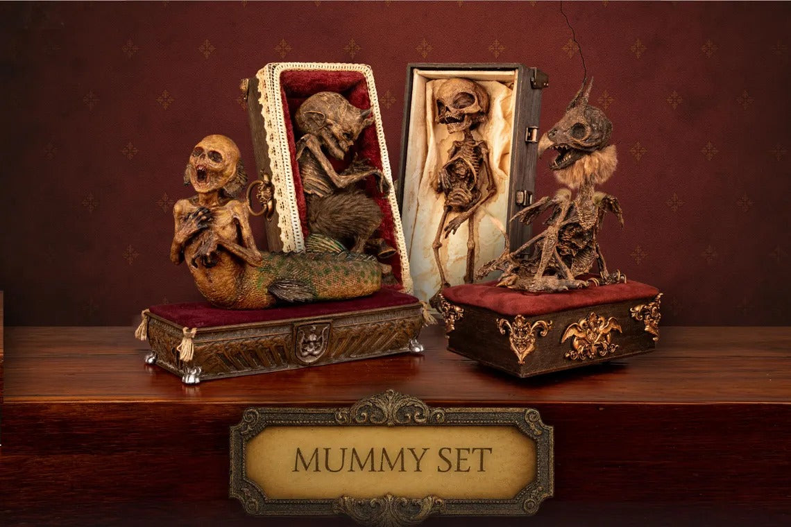 Decorative mummy set in ornate cases on a wooden surface with a dark red background.