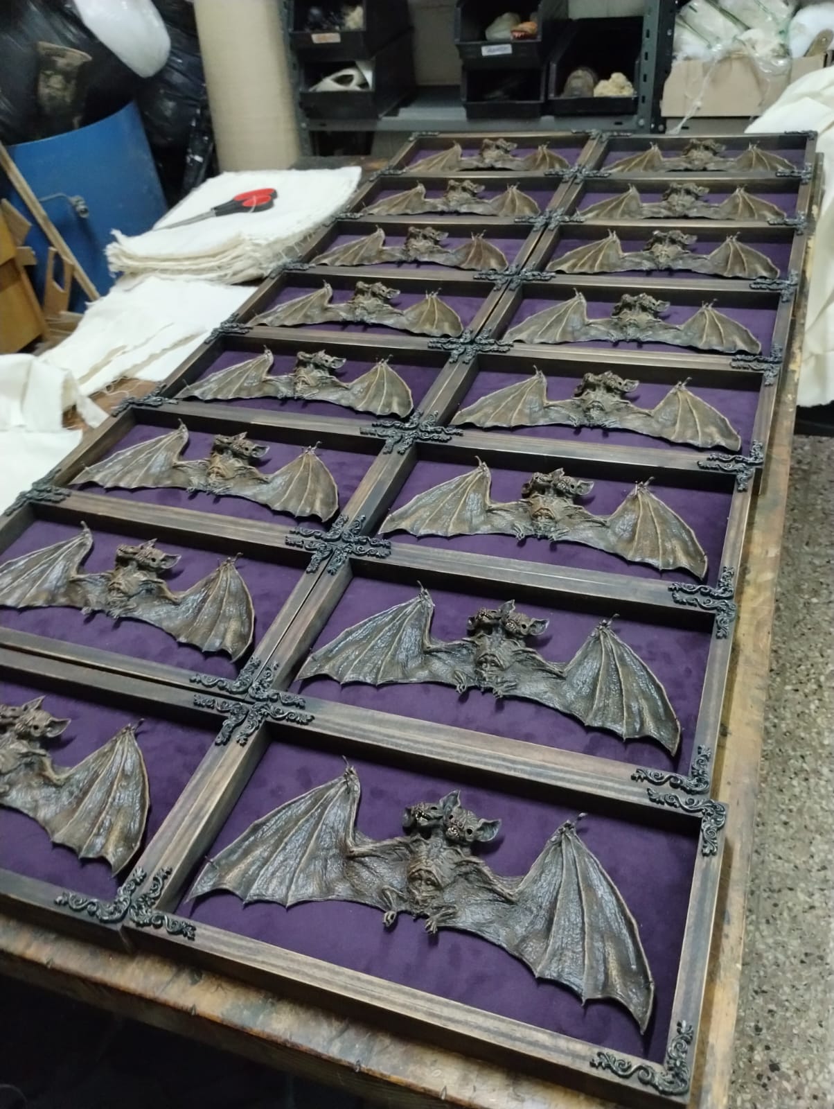 Collection of taxidermy bat figurines on a purple cloth in a wooden display case.